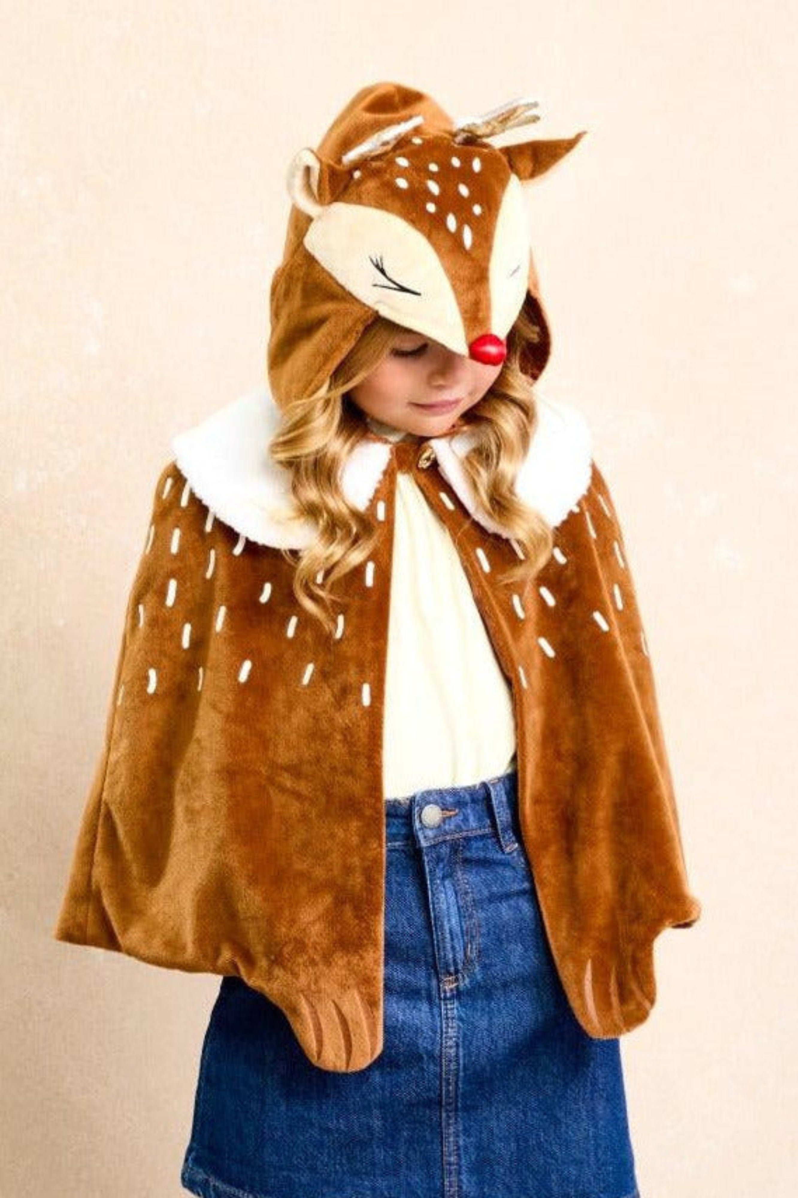 Child wearing a deer-themed cape with a beige background