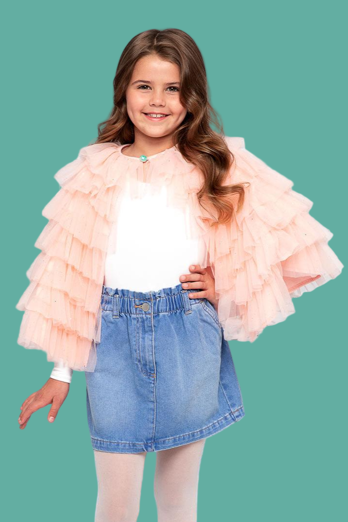 Young girl wearing a pink ruffled jacket, white shirt, and blue denim skirt on a teal background