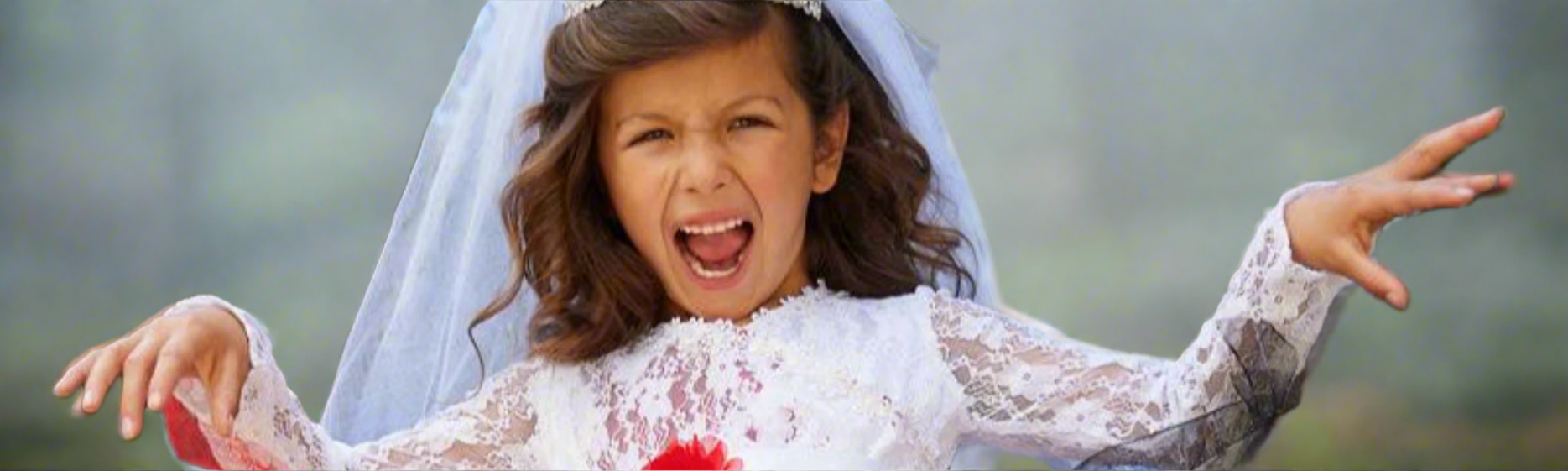 Young girl in a wedding dress with a scary expression outdoors